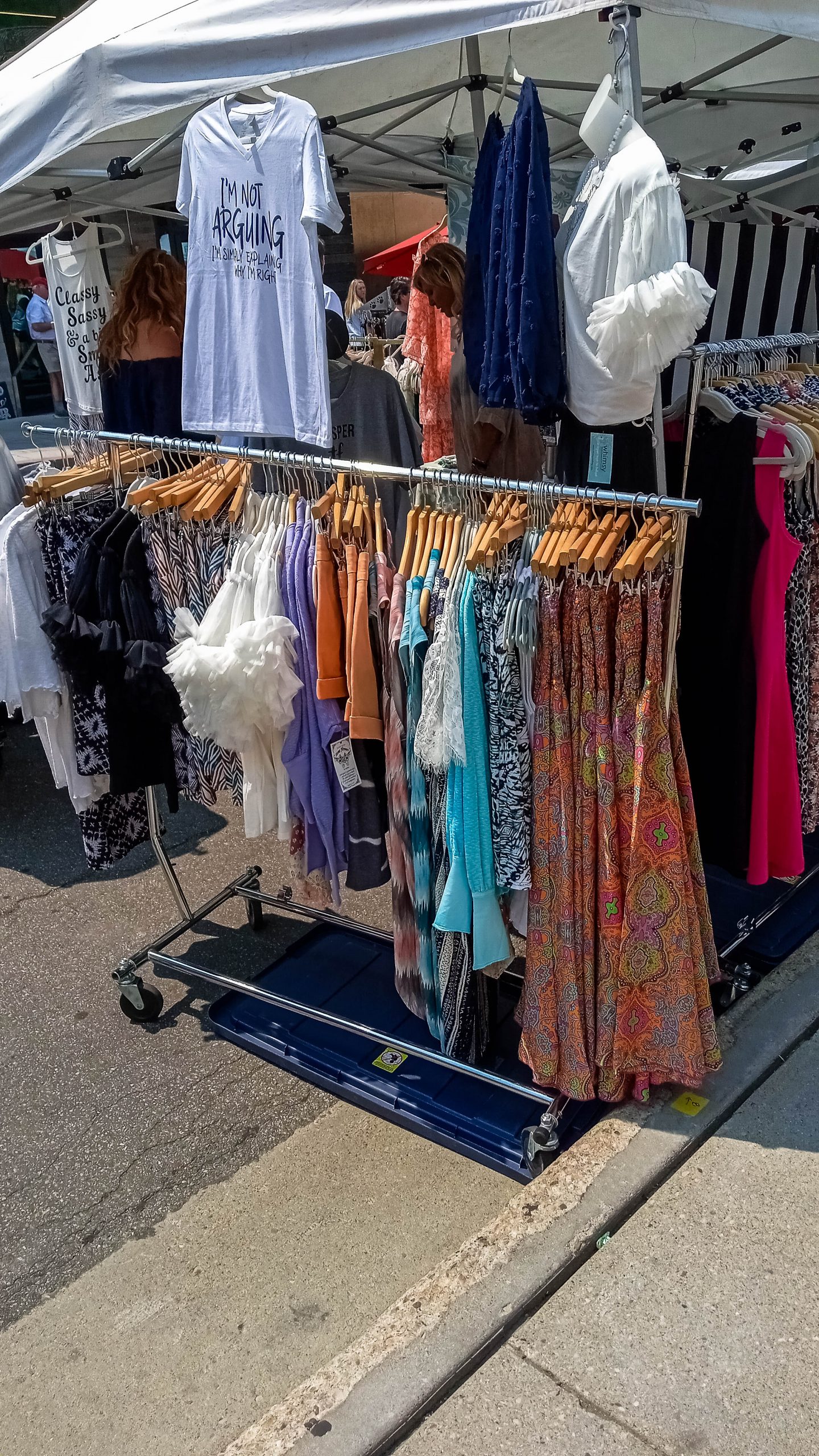 Dresses, shirts, and other clothes hang at this vendor's shop.